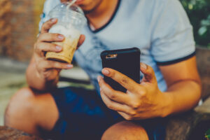 guy sipping frozen coffee on iphone